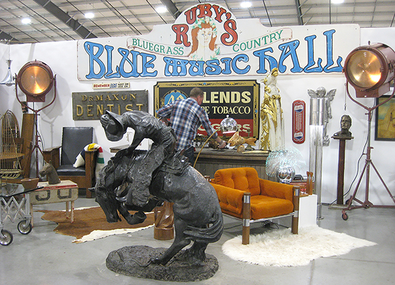 Jamie Hanks of Studio 13, St. John’s, Michigan, signed up for a major space so he could display an enormous music hall sign; a large horse and rider sculpture, $7900; and big movie-set lights, $4800 for the pair. The countertop he was using as a desk at back was sold.