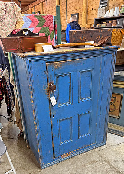 The early blue cupboard from Dean Witham of Red Clover Antiques, Westford, Vermont, who shared a booth with Cooper O&rsquo;Connell, was $745. The signed Shaker box on it was $195; the knife box in original paint, $150; the marquetry document box, $450. We missed the price of the double-sided scoop.