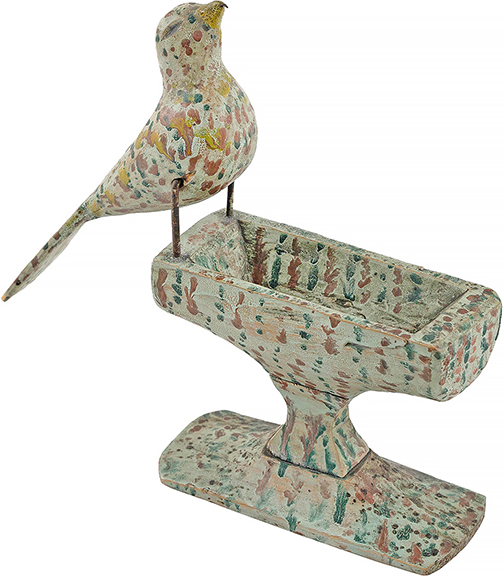 A late 19th- or early 20th-century carved and painted softwood birdbath with a nearly life-size songbird with metal legs and a tiny metal worm in its beak is perched on a diminutive pedestal basin. The bath, in green, red, and yellow speckled paint on the gray-green ground, stands 8