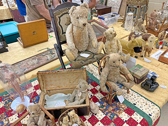 The Steiff 17PAB 1905 white mohair teddy bear in the small trunk has remnants of a white tag by button and shoe button eyes, and was tagged $2850 from Lori Teahen of Teahen’s Treasures, Greenfield, Massachusetts. The Steiff mohair bear in the larger chair with glass eyes and a working growler, 1940s, was tagged $475. The blond mohair bear in the smaller chair is an early Steiff with a blank button, 1905 to 1906, some loss of fur, missing nose and mouth threads, and the paw pads have been covered in felt; it was tagged $1650. The white Steiff teddy bear on the right, 1906-08, with shoe button eyes, replaced pads on feet, was tagged $1950.