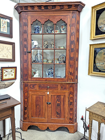 The eye-catching grain-painted finish on this Pennsylvania two-piece corner cupboard found in the dealer space of Greg K. Kramer & Co. was a real winner. It was priced at $10,500. 