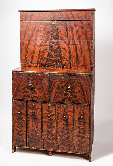 The two-part storekeeper’s desk in original paint decoration, circa 1840, came from Maine. The upper part drops open to shelves above a writing surface, and the bottom is a bank of five locking drawers. Estimated at $500/1000, the 76