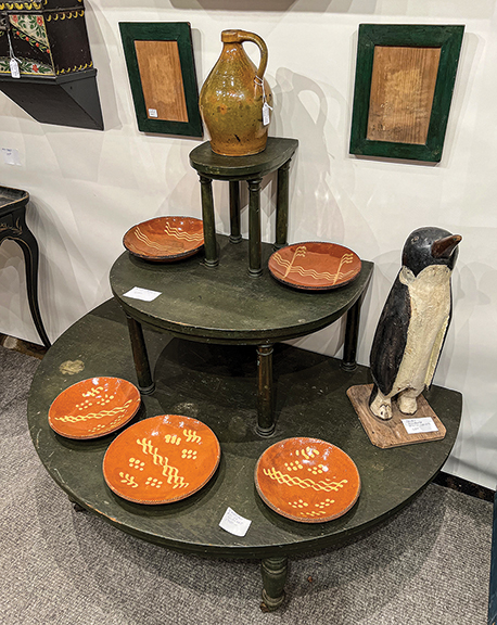 A redware jug, probably from Gonic, New Hampshire, was $650 and sat atop a three-tier plant stand that was also $650 from Jef and Terri Steingrebe of New London, New Hampshire. The two redware slip-decorated plates on the second tier were $650 each; the set of three matched redware plates on the lower level was $1750; and the carved and painted penguin was $2800.