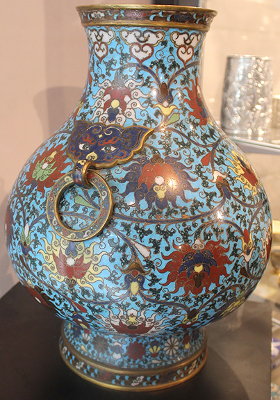 Jonathan Tung of Lotus Gallery, Austin, Texas, stated that this hu (wine vessel) is from the latter portion of the Ming Dynasty, 1570-1620. The gilt and enamel cloisonné body is decorated with vines and lotus blossoms on a blue ground. The ring handles are suspended from sinister cat-like masks. The vessel stands 16