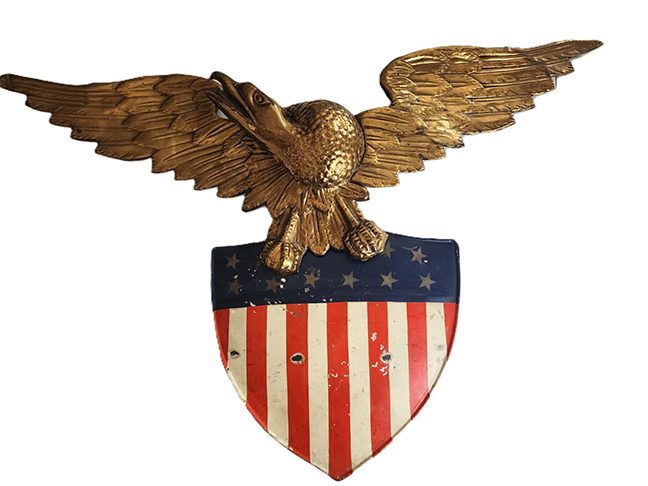 This metal shield and eagle has the flag holders on back. Original paint, good condition. 29 inches x 20 inches.