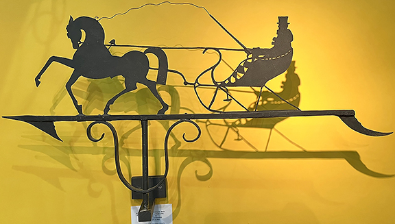 Against a deep yellow backdrop, Heller Washam Antiques, Portland, Maine, offered for $8250 this Art Deco sheet- and wrought-iron horse and sleigh weathervane, circa 1925, 16½