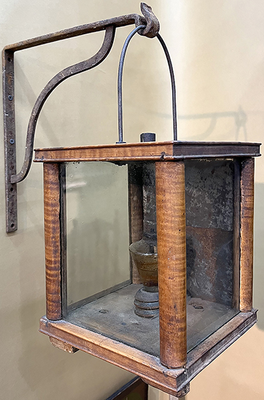 Hilary and Paulette Nolan of Falmouth, Massachusetts, offered for $5800 a rare wooden tiger maple lantern with wavy green-tinted side panels that sits on small squared feet.